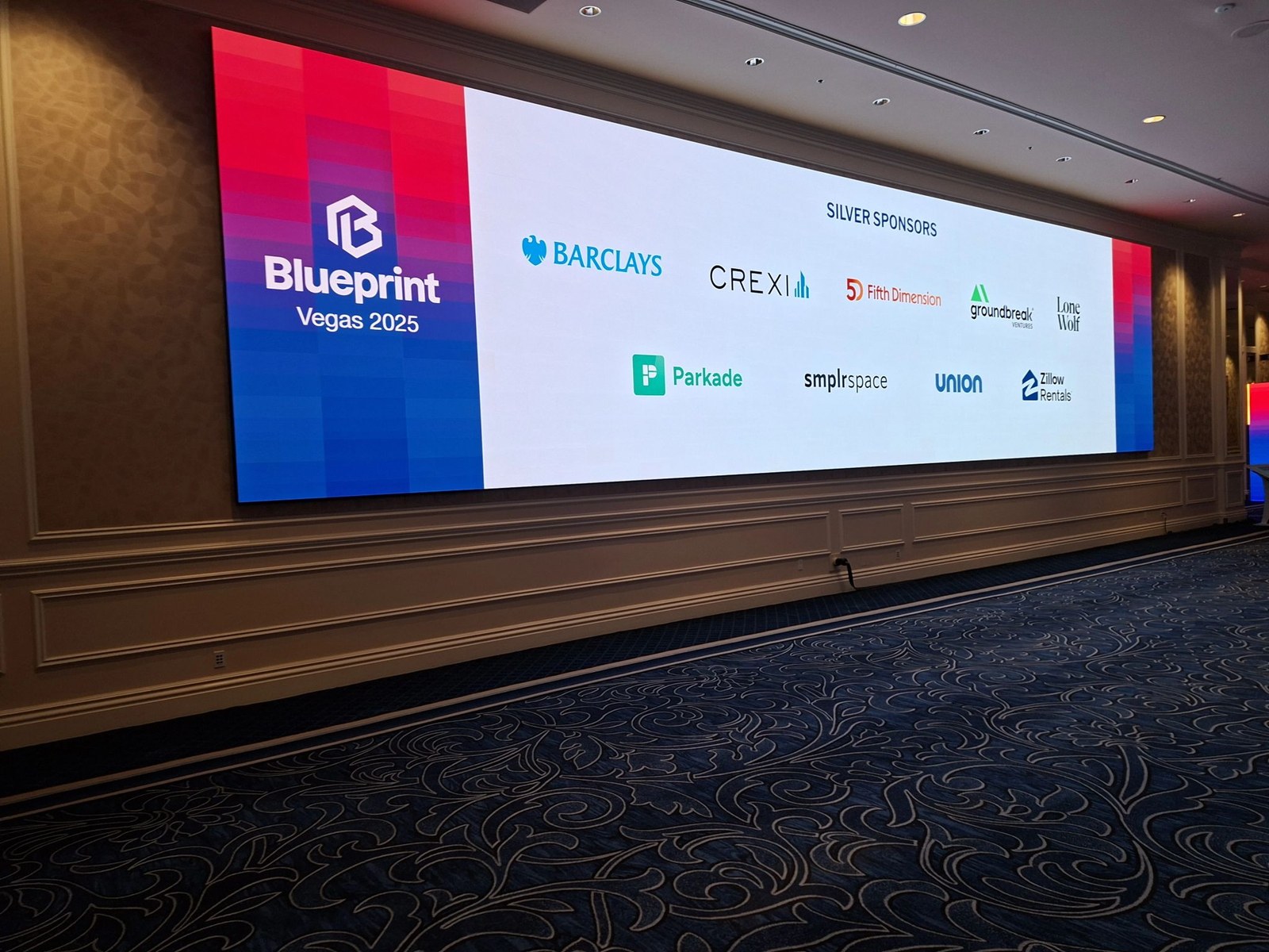 Blueprint Vegas 2025 LED display wall at The Venetian, showing the Silver Sponsor logos: Barclays, Crexi, Fifth Dimension, Groundbreak Ventures, Lone Wolf, Parkade, smlrspace, Union, Zillow Rentals.